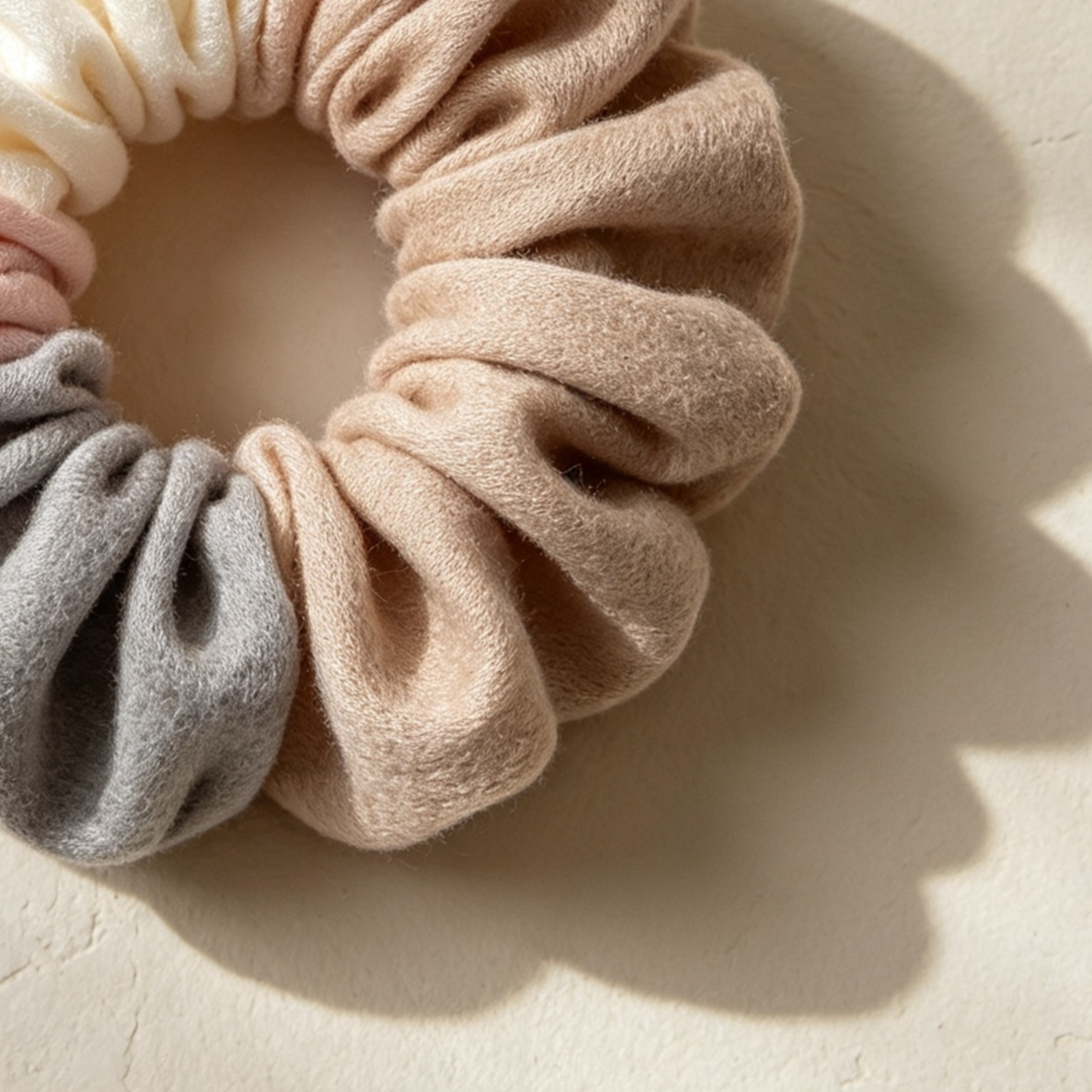 Hand holding multiple plush scrunchies in vibrant colors