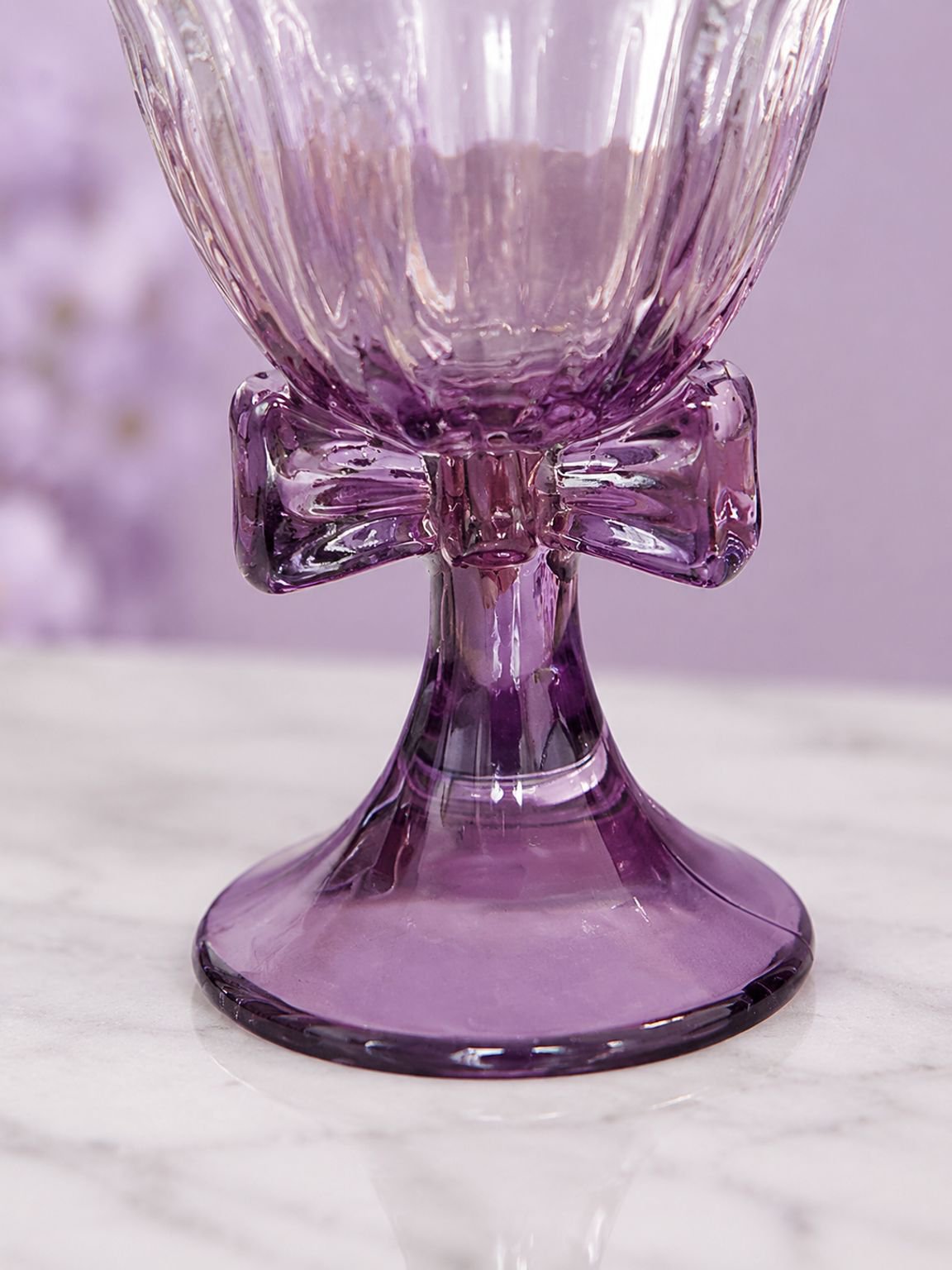 Copa de cristal con lazo púrpura creativo sobre mesa elegante